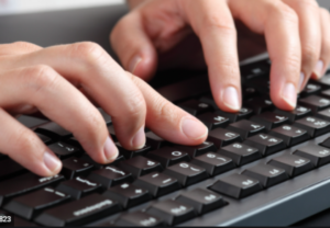 hands typing on a black keyboard